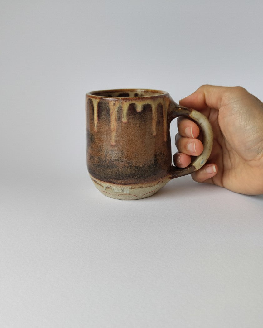 Hand holding a ceramic mug with a textured surface on a light gray background