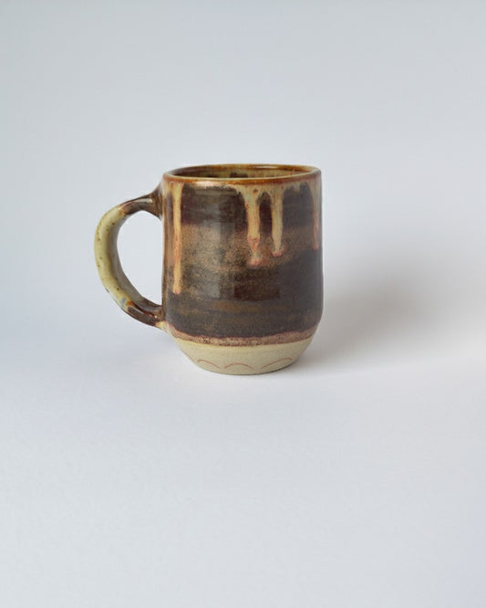 Ceramic mug with brown glaze on a light gray background