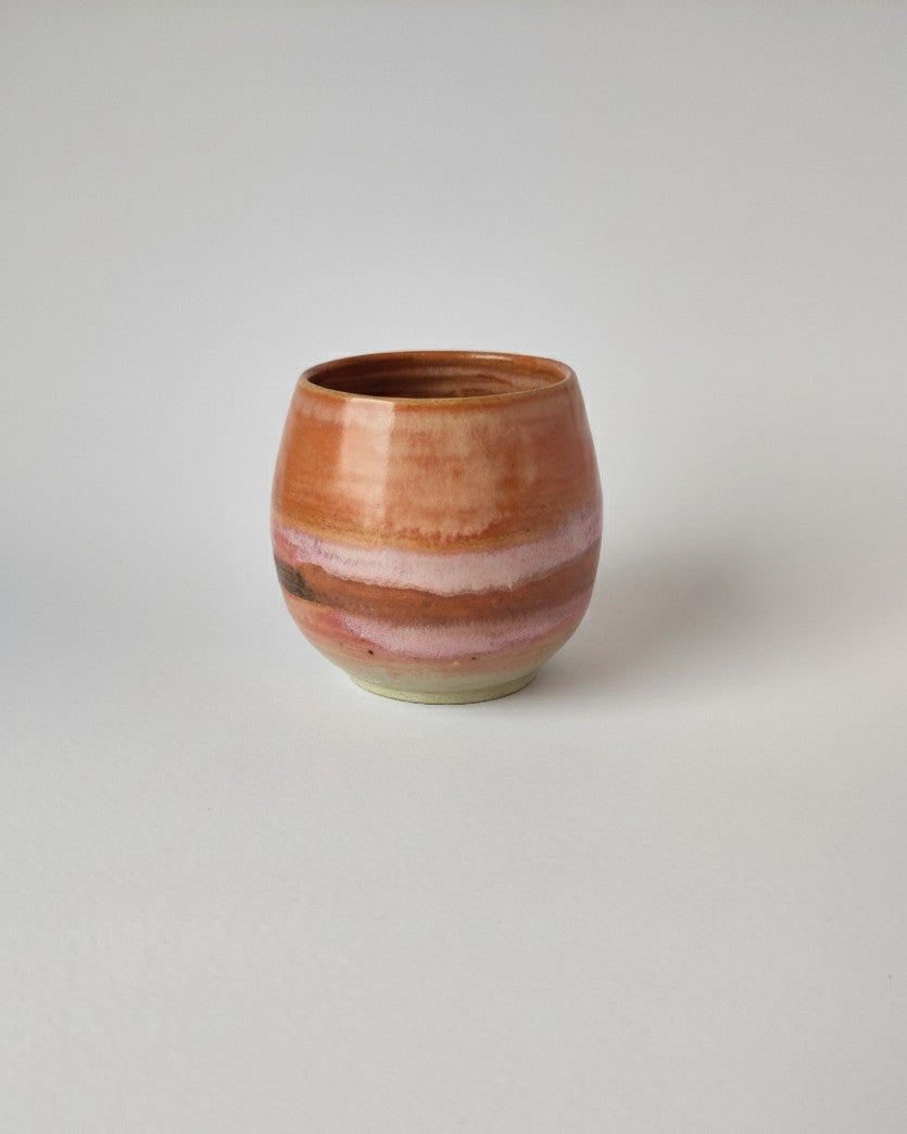 Ceramic cup with multicolored glaze on a light gray background